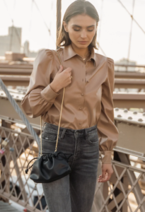 woman in a brown shirt holding a black purse