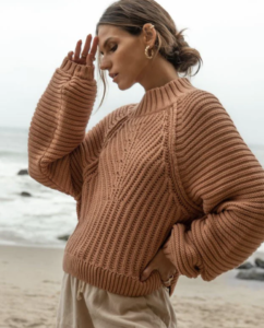 woman on the beach and wearing a blush colored sweater