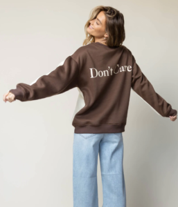 woman wearing a cream and brown hoodie that says, don't care.