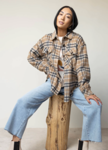 woman with a plaid jacket sitting on a piece of wood